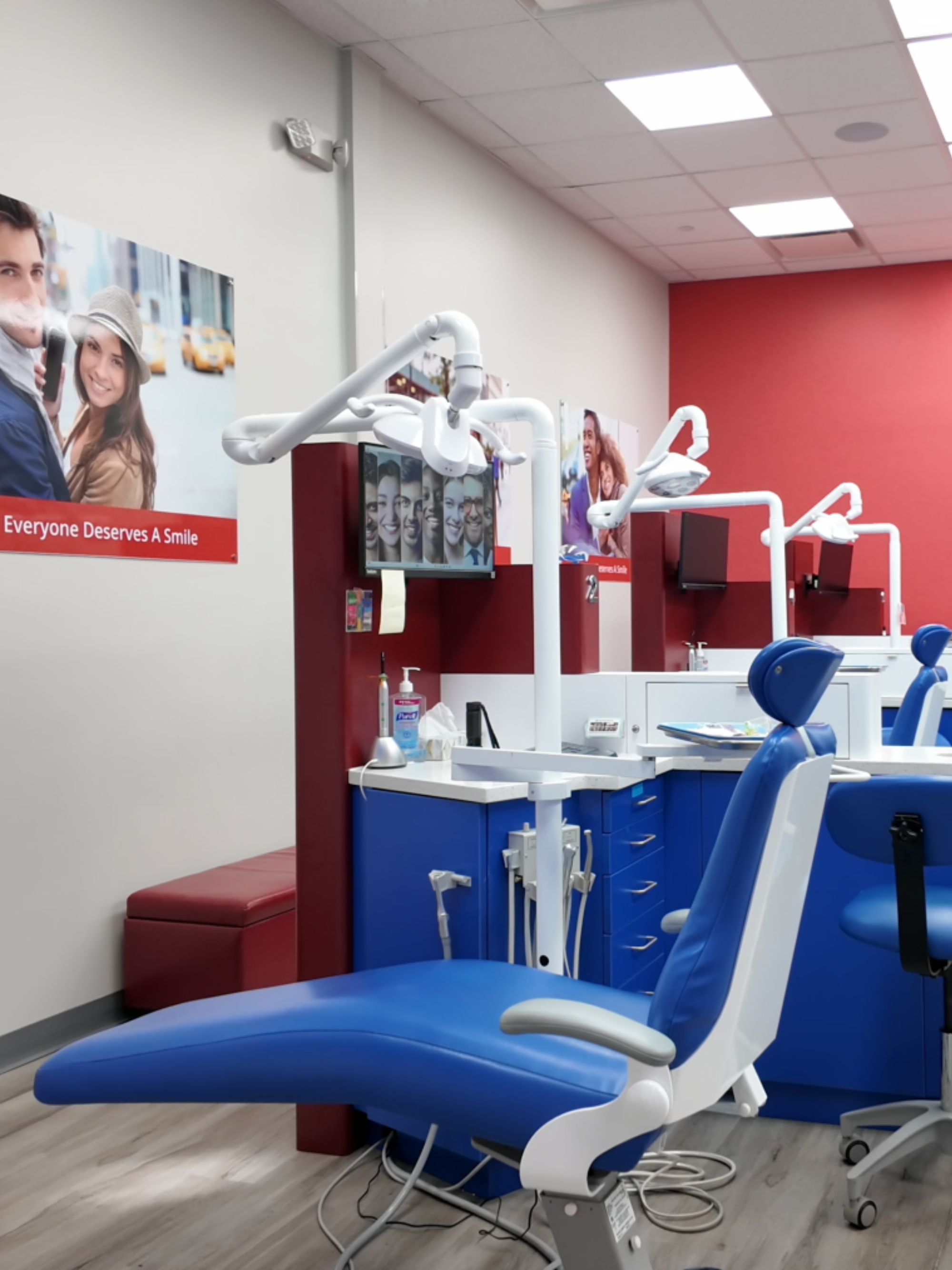 Dental office interior with blue chairs, dental equipment, and promotional posters on the wall for Diamond Braces.