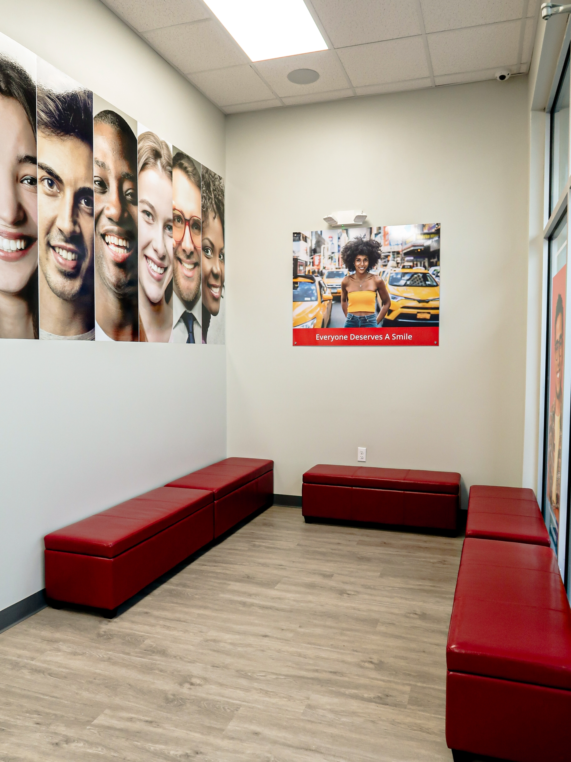 Waiting room with red benches, wall art of diverse faces, and a poster on the wall inside of a Diamond Braces dentist office in New York City.