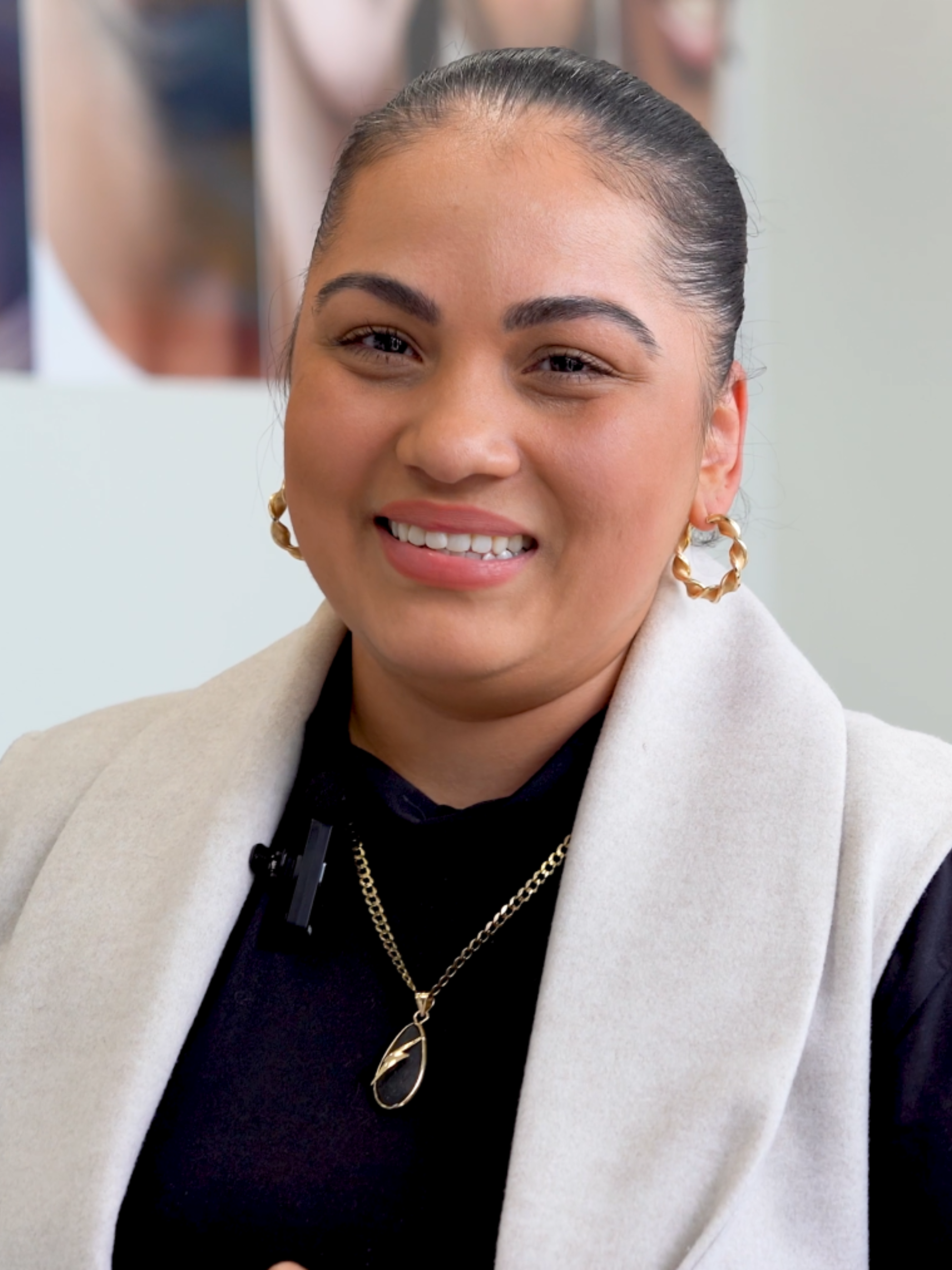 Dental Office Manager wearing a light-colored coat and gold jewelry, smiling.