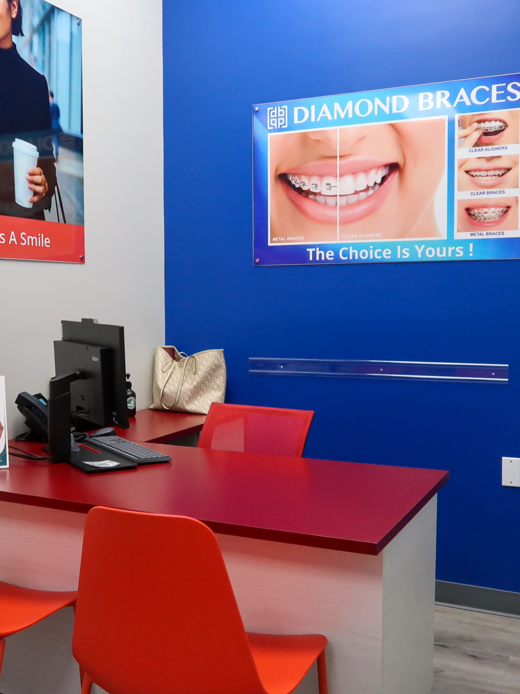 Dental office interior with red desk and chairs, blue wall with Diamond Braces advertisement.