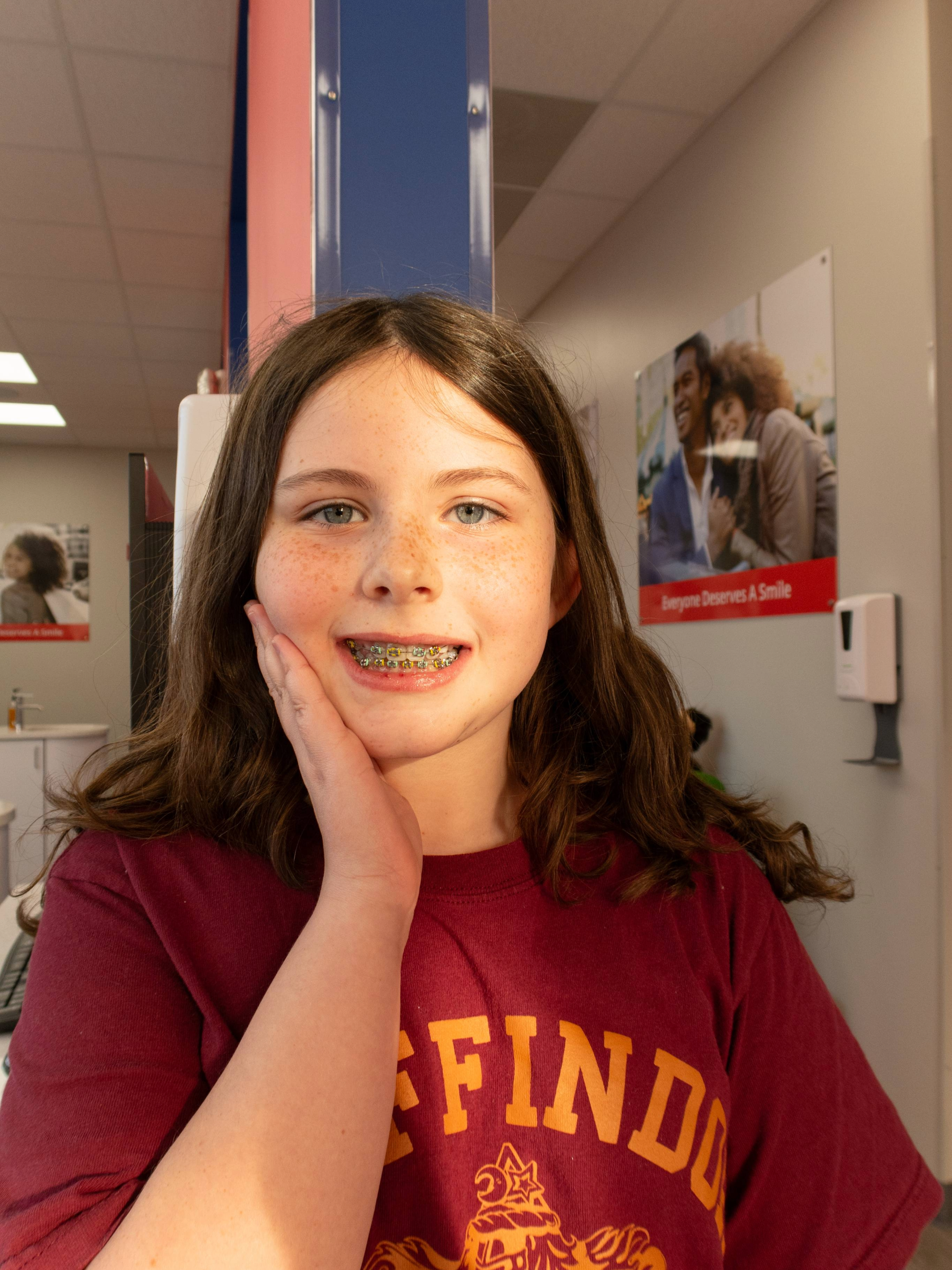 Dental care patient wearing ceramic braces in a room with posters on the wall.