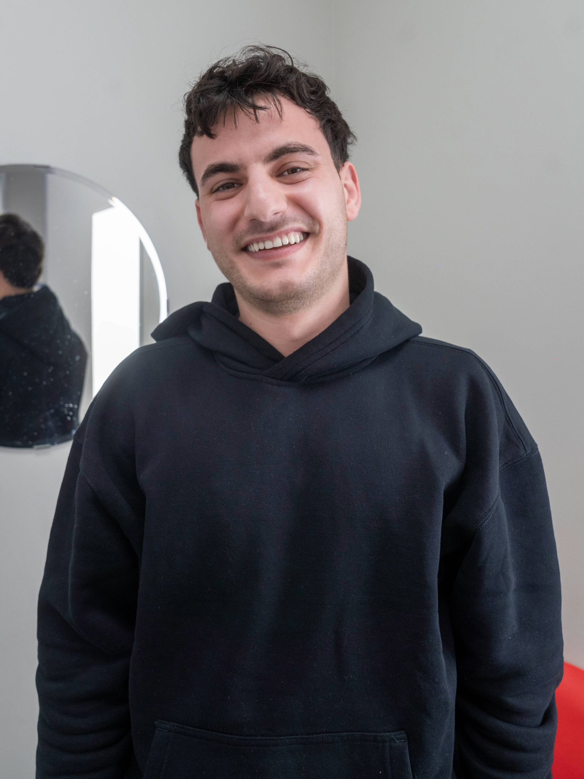 Dental care patient wearing a dark hoodie standing against a plain wall inside of a Diamond Braces orthodontist office.