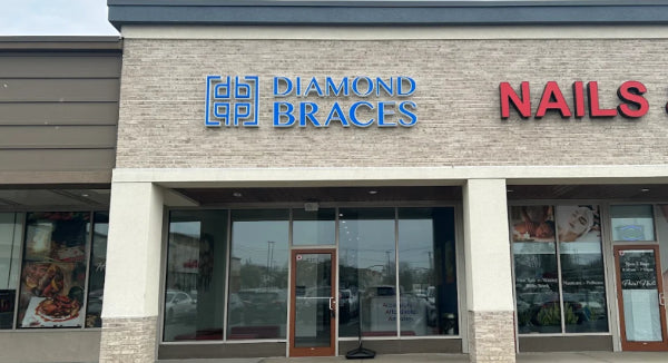 Building facade with 'Diamond Braces' and 'Nails' signs in Long Island strip mall.