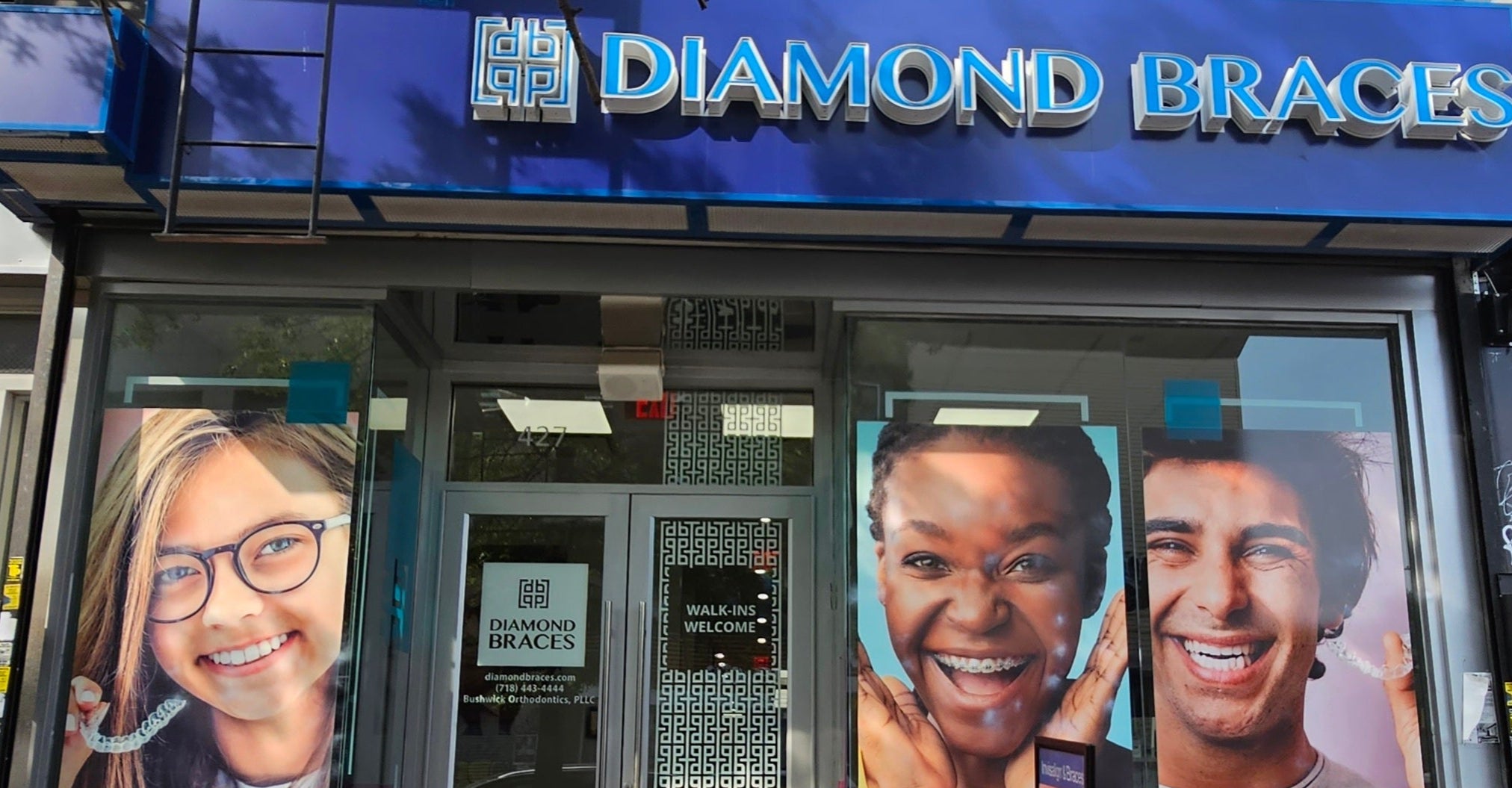 Dental clinic storefront with Diamond Braces sign and promotional images of people on the glass doors in Bushwick.
