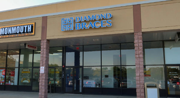 Diamond Braces dental office with large glass windows and a beige exterior in a Wall, New Jersey plaza.