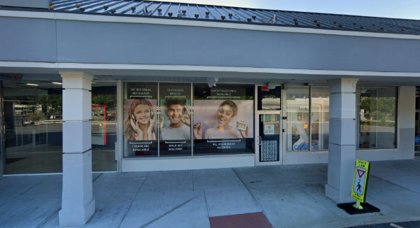 Diamond Braces dental clinic storefront in Yonkers with large windows displaying advertisements, including images of people.