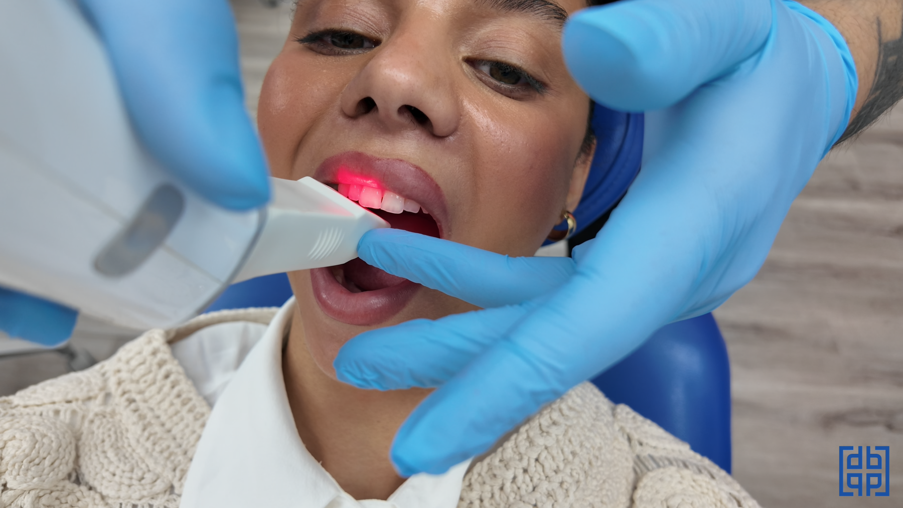 A close up image of a Diamond Braces orthodontist with blue gloves using a dental care tool on a young woman.
