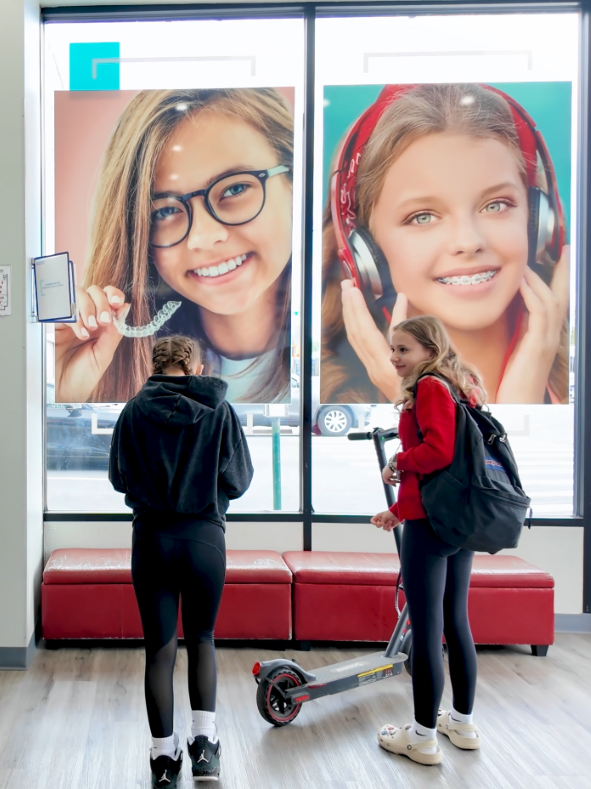 Two kids who just got their braces colors changed are standing in a Diamond Braces office waiting area.