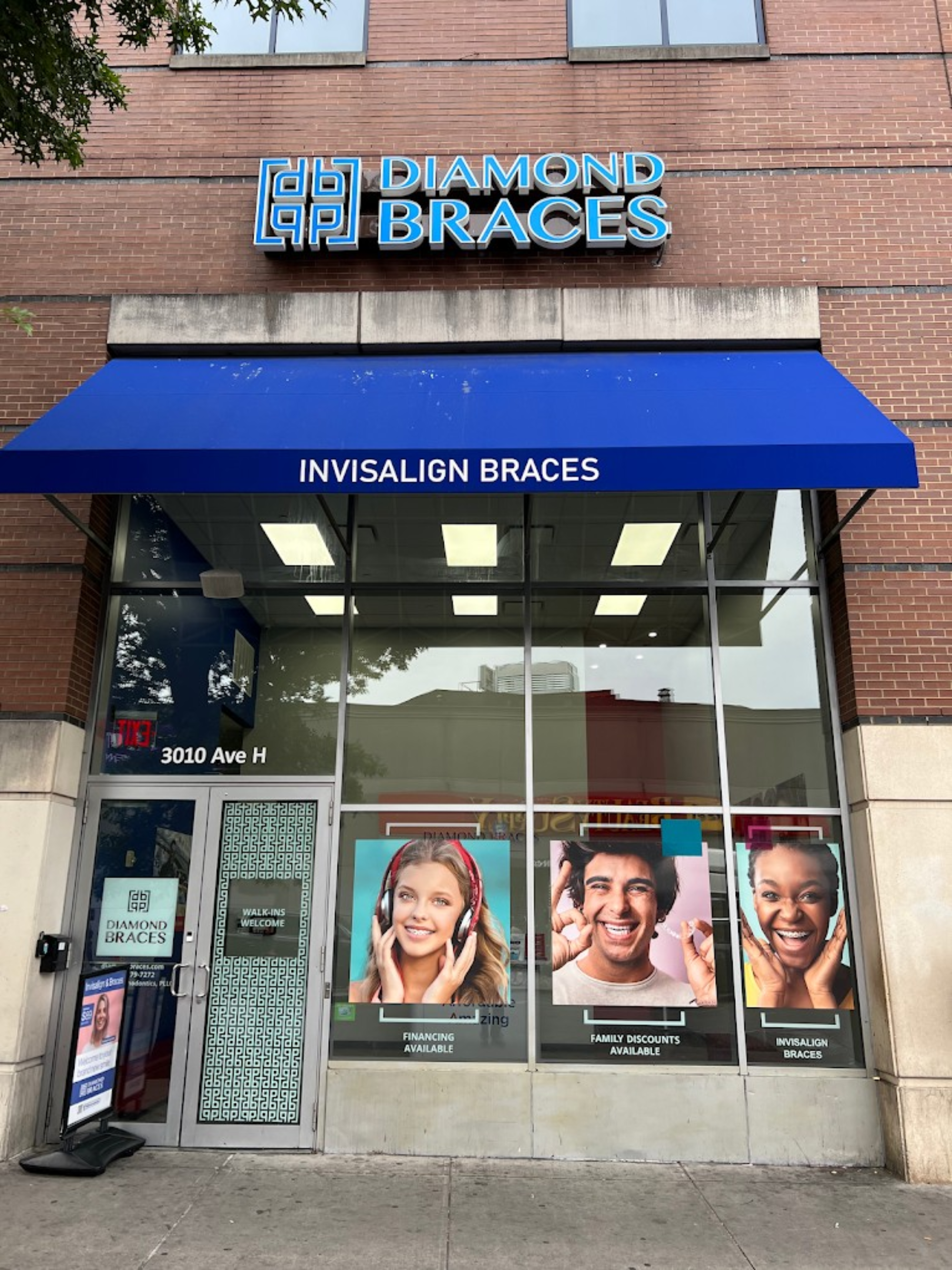 Diamond Braces dentist office with a blue awning and promotional posters for braces for kids and Invisalign.