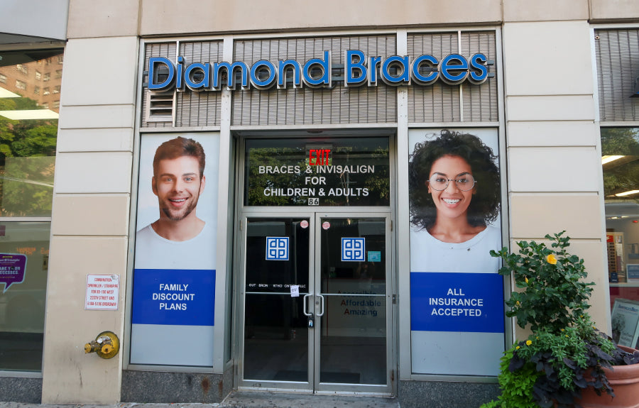 Diamond Braces dental clinic entrance with promotional posters on a building facade in Marble Hill.
