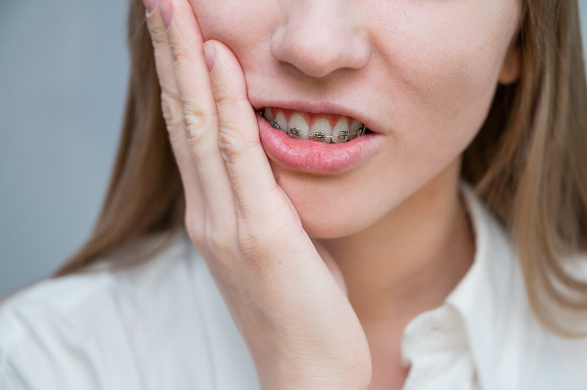 Woman holding her cheek, possibly indicating toothache or dental issue